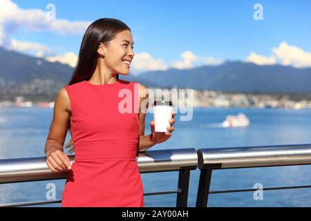 Happy multiethnic business woman enjoying her morning coffee at work break in beautiful nature view in vancouver city, downtown. Urban lifestyle, businesspeople working in coal harbour. Stock Photo