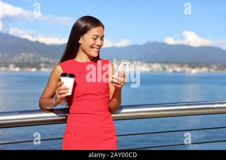 Businesswoman drinking coffee using mobile phone app to play video games online. Asian woman relaxing. Work urban city lifestyle. Stock Photo