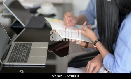 Side view of  two businesspeople discussing on their work while looking on notebook Stock Photo