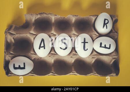Easter festive eggs in the carton with text. Easter text written on white eggs. Happy Easter, spring festive holidays concept on the colorful background Stock Photo