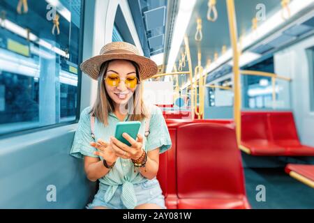 young asian woman checking timetables of city subway traffic online by smartphone application. Modern urban transportation concept Stock Photo