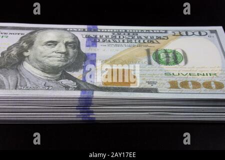 Benjamin Franklin stack of dollar bills in one hundred dollars on a black background. Stock Photo
