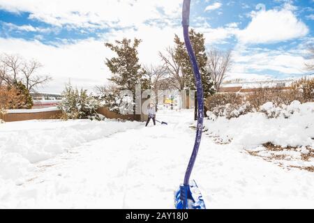A six year old boy shoveling snow in driveway Stock Photo