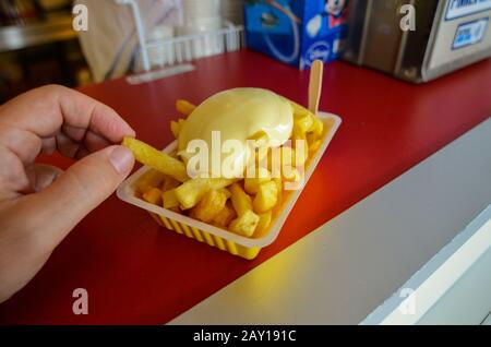 Oosterscheldekering, the Netherlands, August 2019. The main course at a street food kiosk: French fries. A portion is ready to be enjoyed, a hand is t Stock Photo