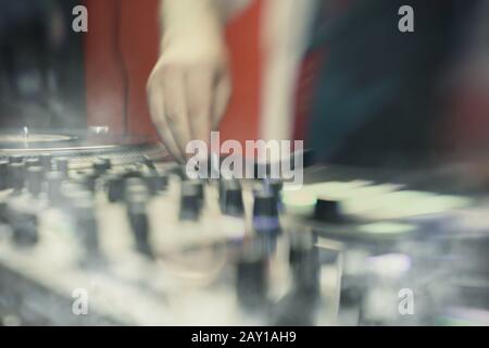 Blurred background with concert dj playing music on stage.Hip hop disc jockey mixes musical tracks with sound mixer and turntables on party.Dynamic mo Stock Photo