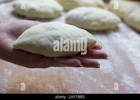 On the palm of a woman cook cooked bun stuffed ready for baking in the oven. Great dessert for tea in the cold season. Stock Photo