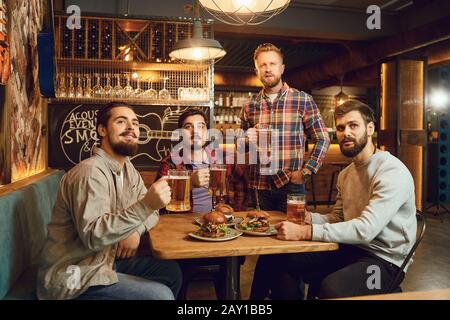 A group of guys watching sports on tv in a pub bar. Stock Photo