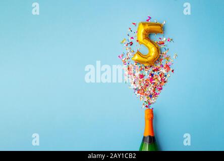 5th anniversary champagne bottle balloon pop Stock Photo