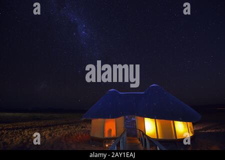 Huts, chalets of Sossus Dune Lodge at night with milky rhinestones Stock Photo