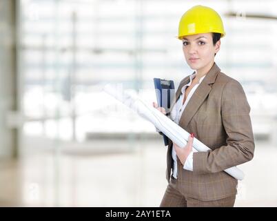 Female architect holding blueprints with helmet on head Stock Photo