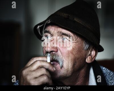 Closeup Artistic Photo of Aged Man With  Grey Mustache Smoking Stock Photo