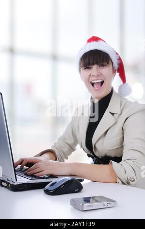 Pretty female wearing santa hat, holding organiser, using mobile, smiling in office Stock Photo
