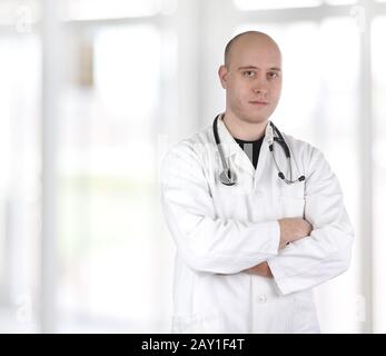 Smiling confident doctor standing with hands crossed isolated on white background Stock Photo