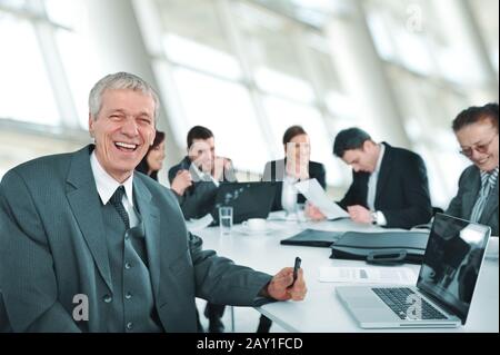 Senior businessman at a meeting. Group of colleagues in the background Stock Photo