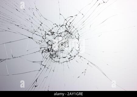 Cracked broken glass from a blow in the window on a light gray background. Cracks concept for design. Stock Photo