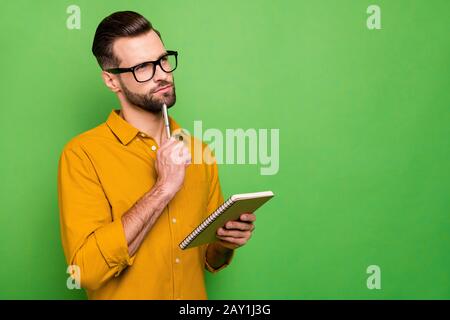 Close-up portrait of his he nice attractive pensive bearded guy in casual formal shirt student writing creating business plan isolated on bright vivid Stock Photo