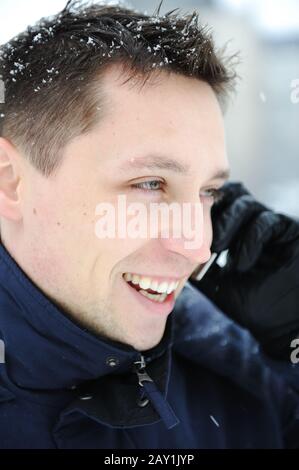 Young male adult speaking on phone at winter snow time Stock Photo