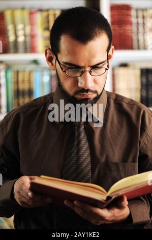 Young man reading book in library Stock Photo
