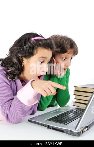 Two surprised girlfriends in front of laptop and stack of books Stock Photo