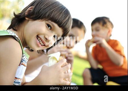 Small group of children in nature eating snacks together Stock Photo