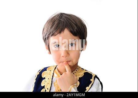 Cute little kid wearing traditional clothes  holding a finger on his lips Stock Photo