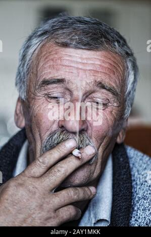 Common elderly man with mustache smoking cigarette Stock Photo
