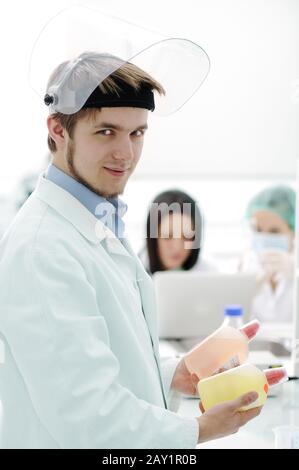 Young medical worker with glass mask working with his team in lab Stock Photo