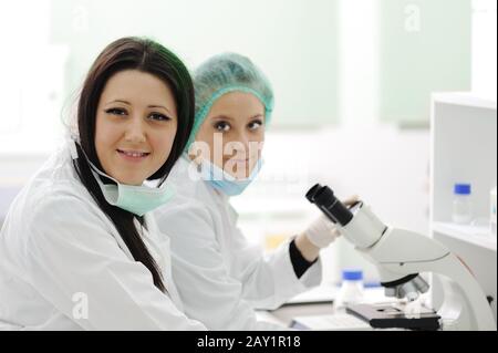 Two female scientists working at the laboratory with microscope Stock Photo