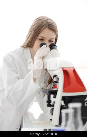 Pretty female researcher using a microscope in a lab Stock Photo