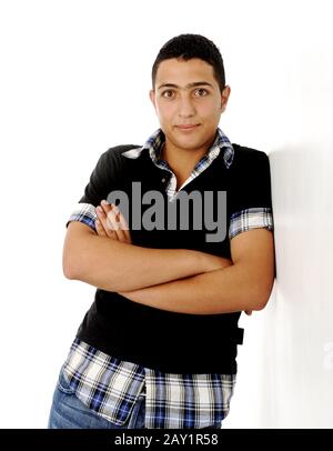 Closeup photo of a middle eastern guy standing against the wall with folded arms isolated Stock Photo