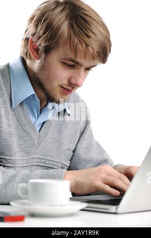 Young man using a laptop. Typing. Cup of coffee beside. Stock Photo