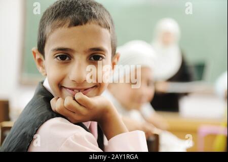 Positive kid in classroom smiling and looking in camera Stock Photo