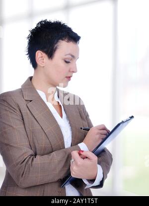 Portrait of a young female entrepreneur taking notes inside a modern building with big glass windows Stock Photo
