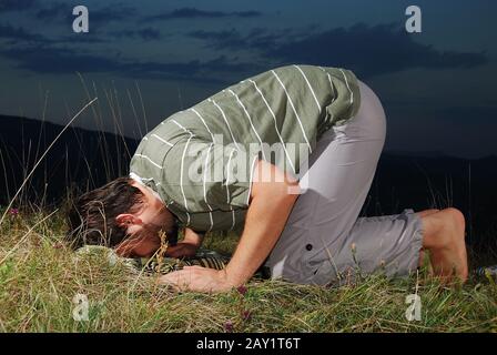 Young muslim man is praying on meadow Stock Photo