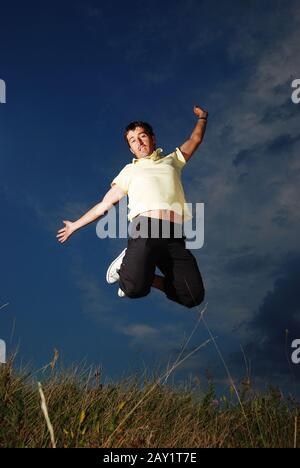 Young happy man is jumping on green meadow Stock Photo