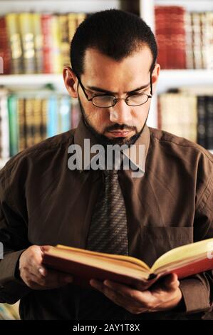 Young man reading book in library Stock Photo