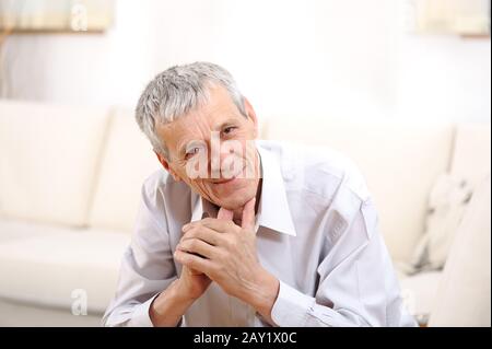 Happy relaxed elderly  man on sofa Stock Photo