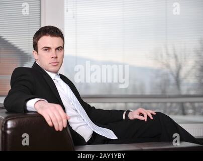 Businessman sitting on leather sofa in office Stock Photo