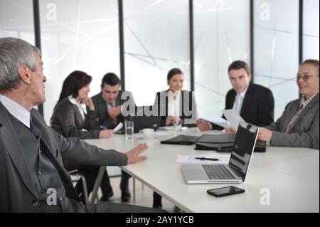 Senior businessman at a meeting. Group of colleagues in the background Stock Photo