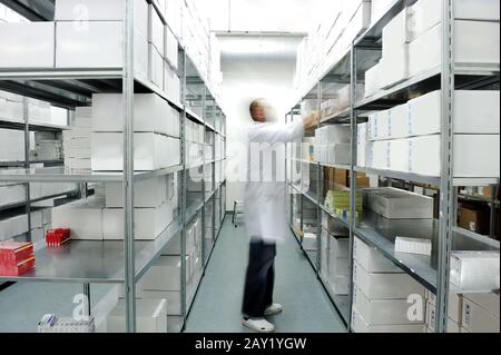 Worker putting boxes together on shelves in modern warehouse Stock Photo