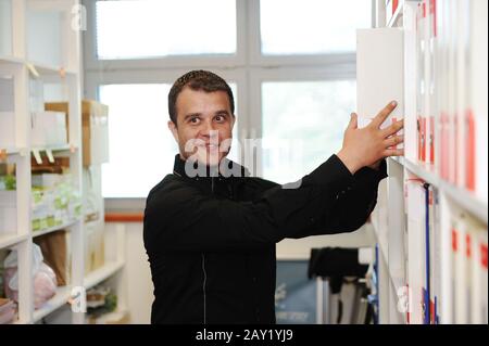 Man working at office putting folders together on shelves Stock Photo