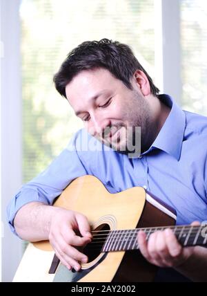 Man playing guitar and relaxing at home Stock Photo