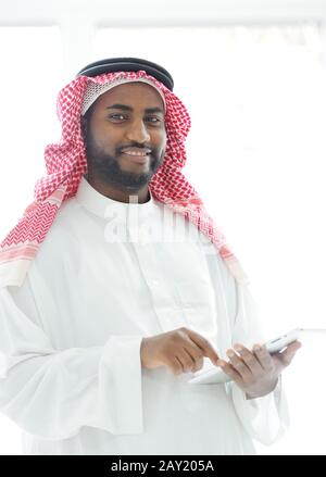 Middle eastern man with gulf clothes using tablet at office Stock Photo