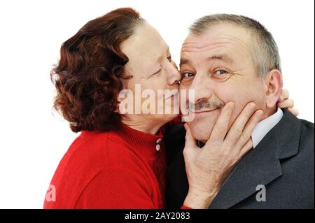 Senior woman kissing in a cheek her husband isolated over white background Stock Photo