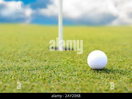 Golf ball at hole on grass field Stock Photo