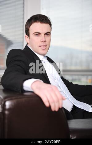 Businessman sitting on sofa in office Stock Photo