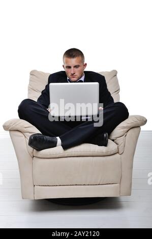 Executive sitting on the armchair cross-legged with laptop Stock Photo