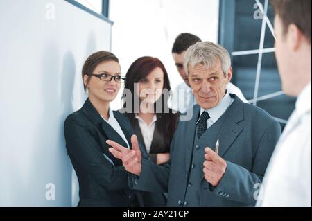 Small business team in the office in front of a whiteboard discussing a project Stock Photo