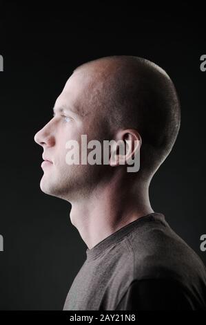 Profile of white bald man in his twenties in dark Stock Photo