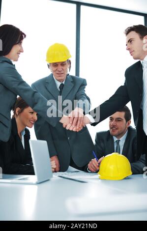 Male and female executives shaking hands in front of colleagues Stock Photo